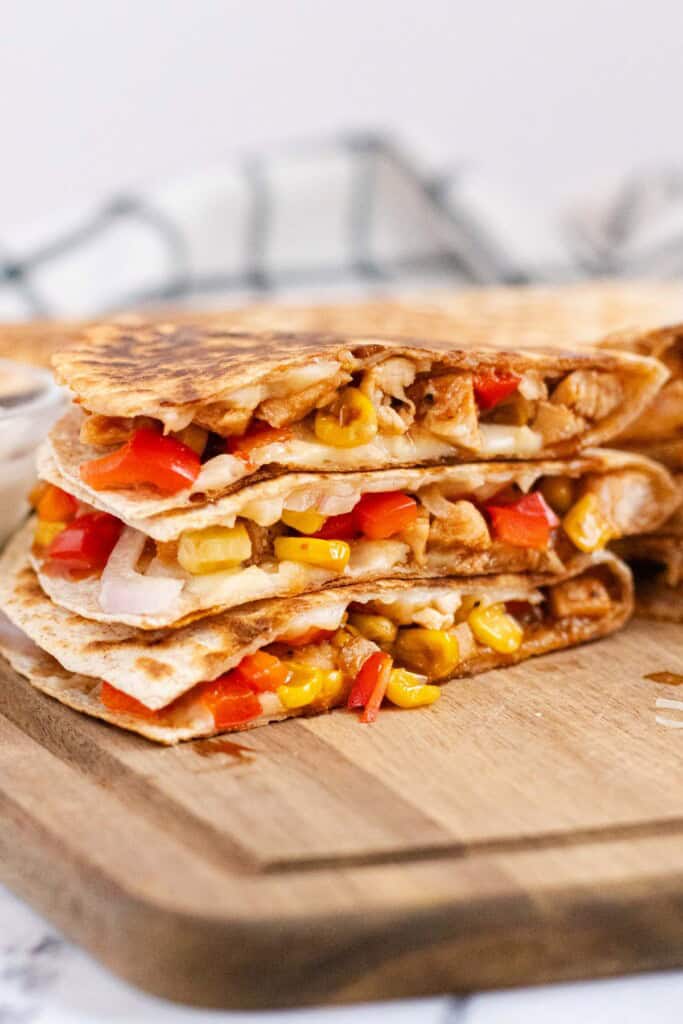 BBQ chicken quesadilla cut into wedges and stacked on a cutting board.