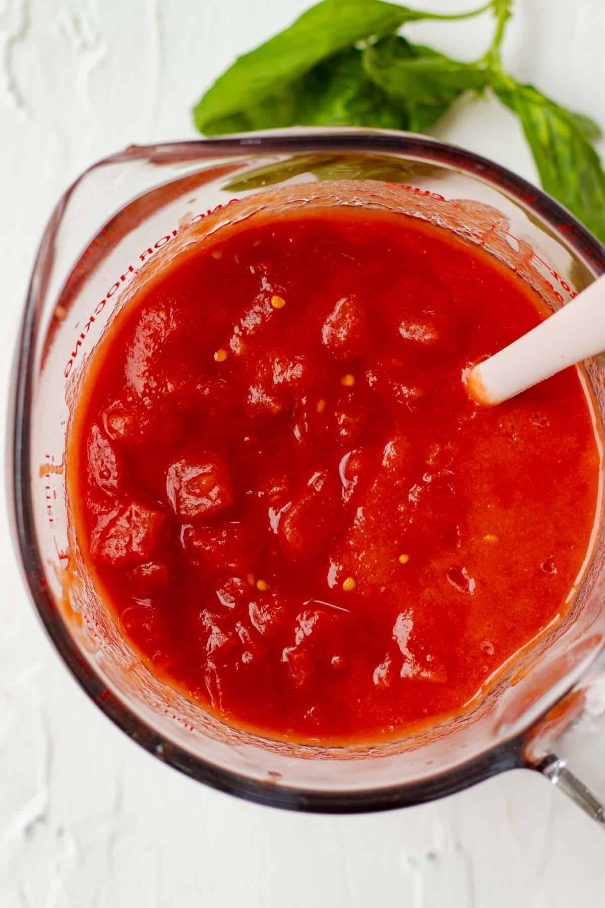 Blended and diced tomatoes in a glass container.