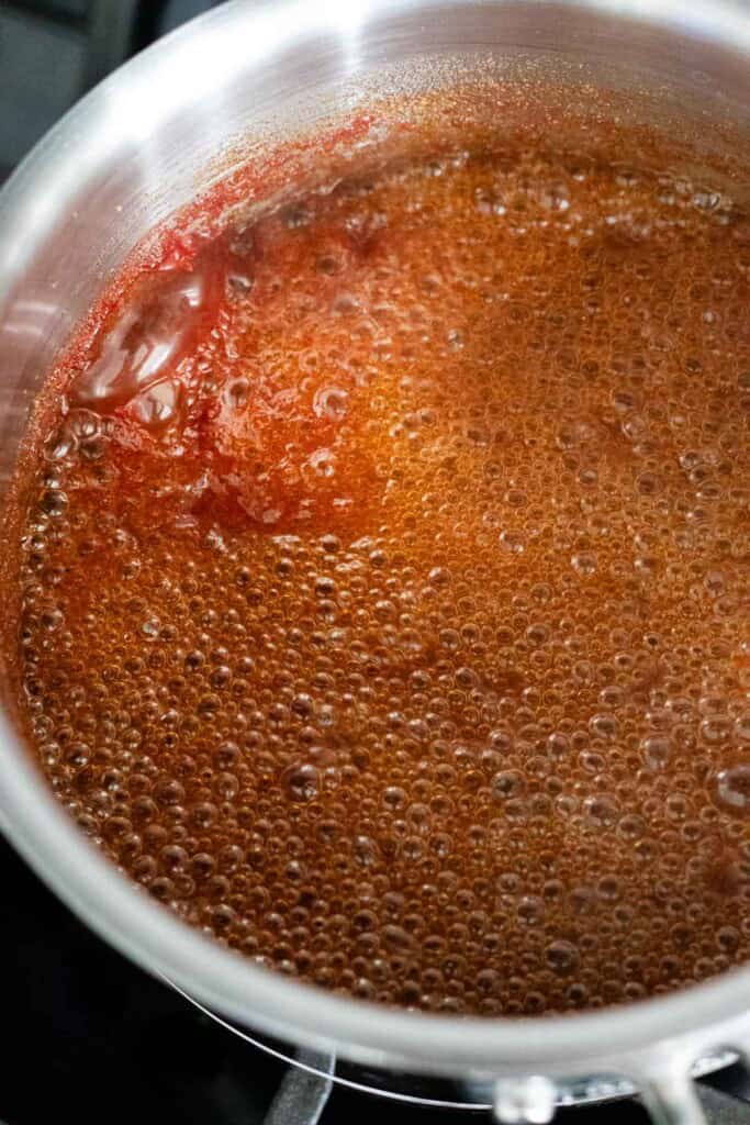 Barbecue sauce is boiling in a stainless steel saucepan.