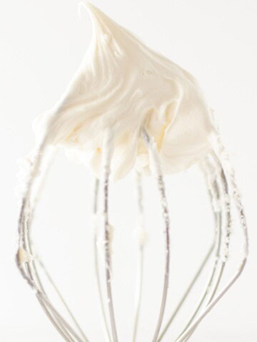 A swirl of cream cheese buttercream on the tip of a whisk attachment.