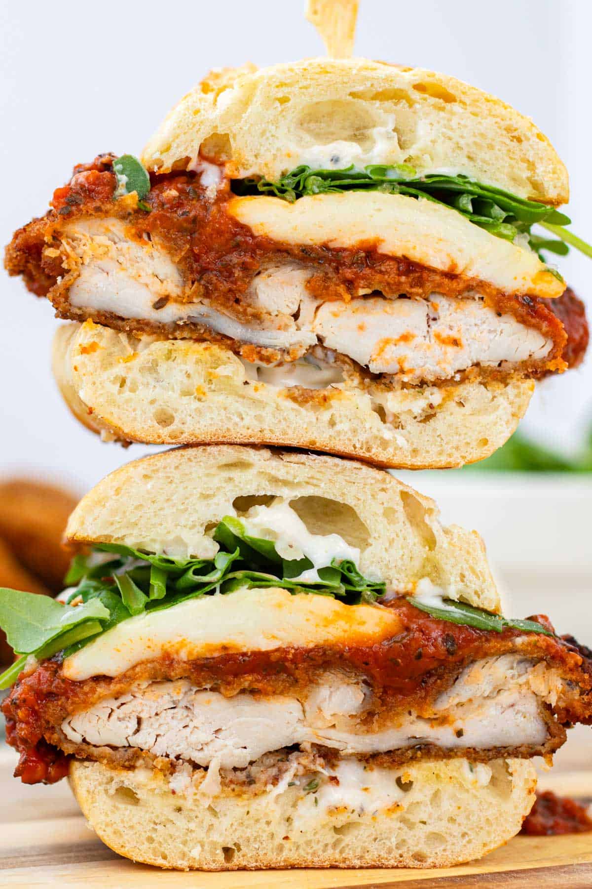 A chicken parm sandwich cut in half and stacked.