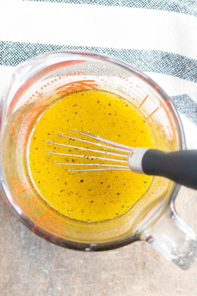 Whisking together the dressing for the bean salad in a glass container.