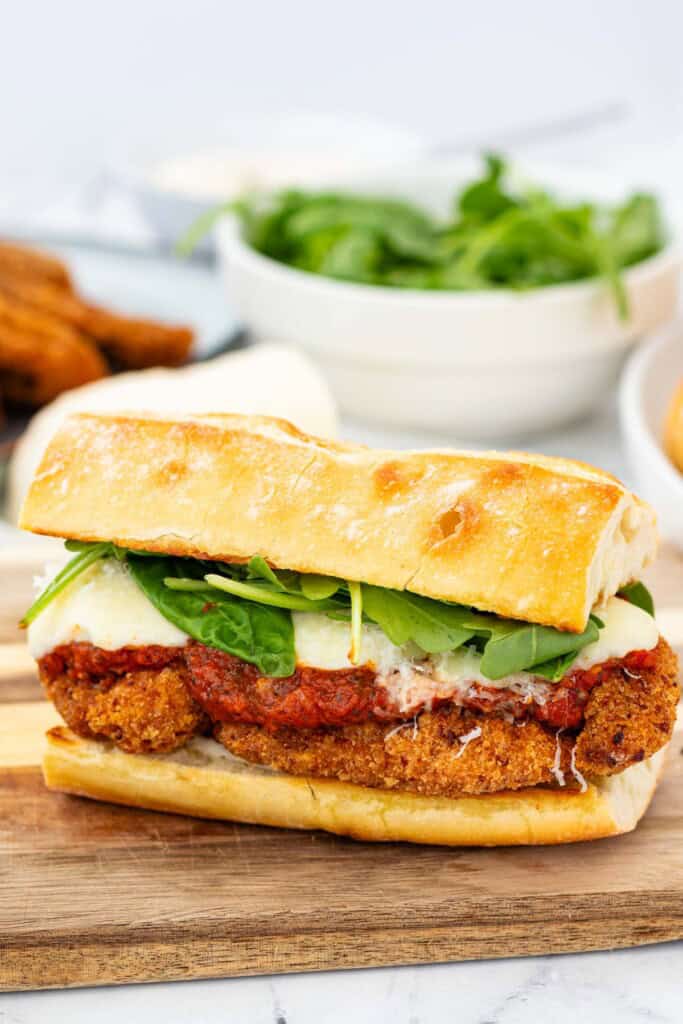 Adding the arugula and top bun to the sandwich.