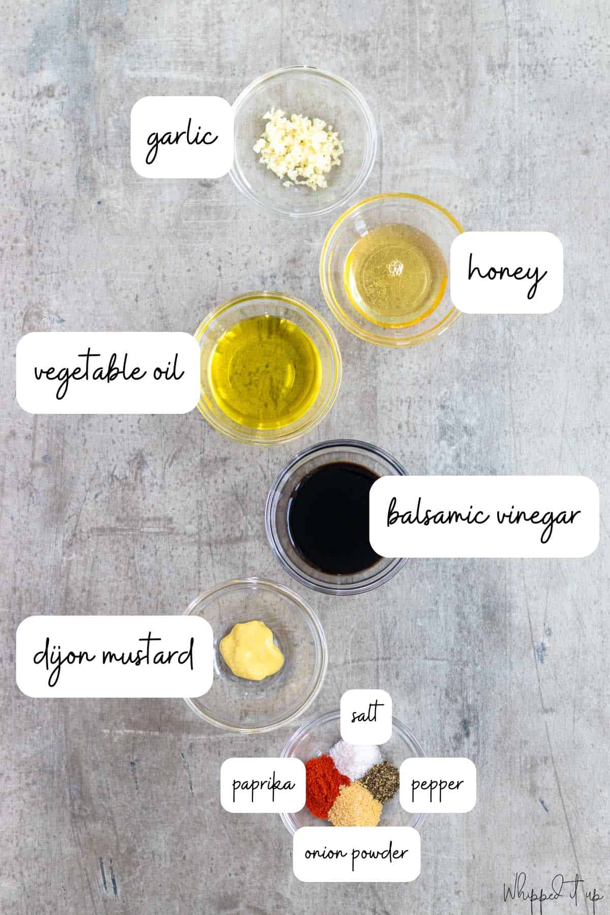 Ingredients for the chicken marinade in glass bowls on a concrete counter.