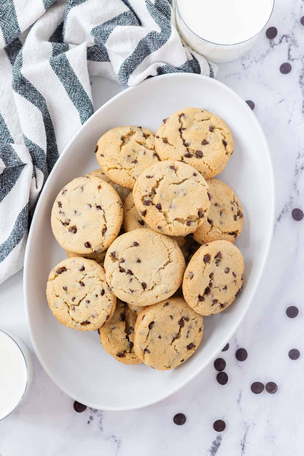 An oval white serving tray piled with vegan chocolate chip cookies.