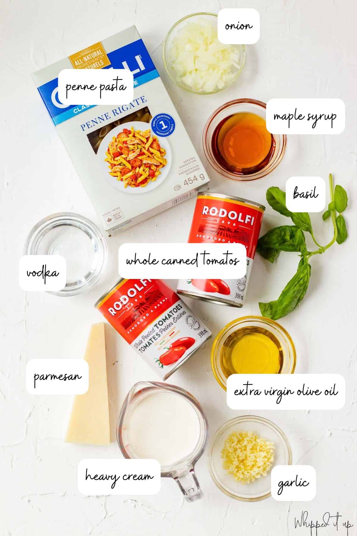 Ingredients to make vodka sauce are measured out in glass bowls on a white background.