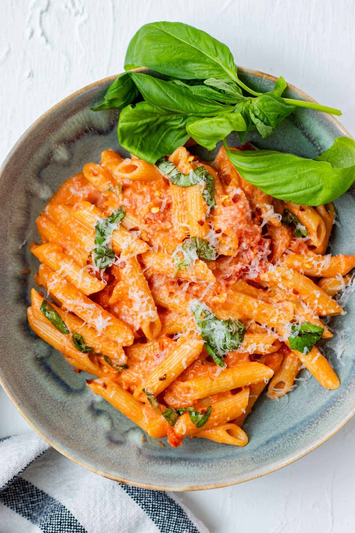Penne alla vodka in a blue bowl with creamy vodka sauce, parmesan cheese, and fresh basil.