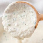 Horseradish sauce running off of a wooden spoon.