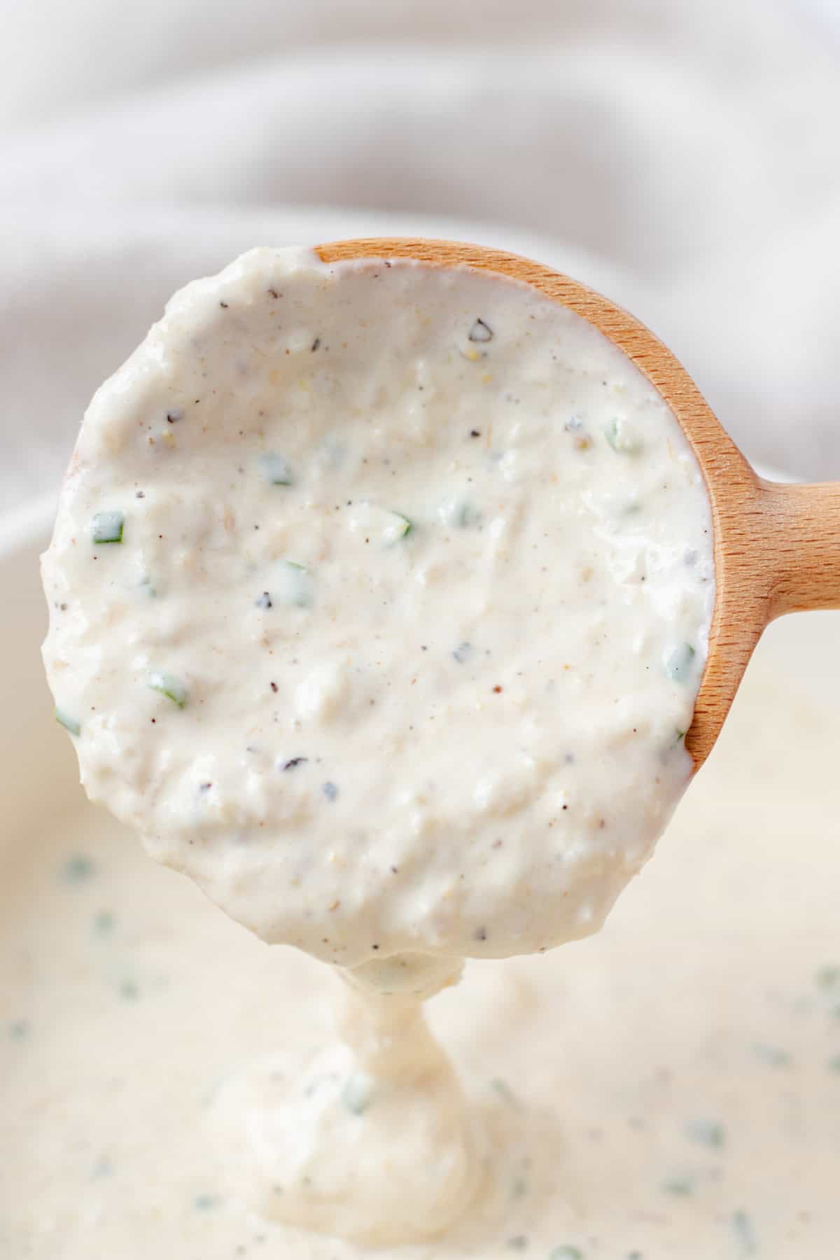 Horseradish sauce running off of a wooden spoon.