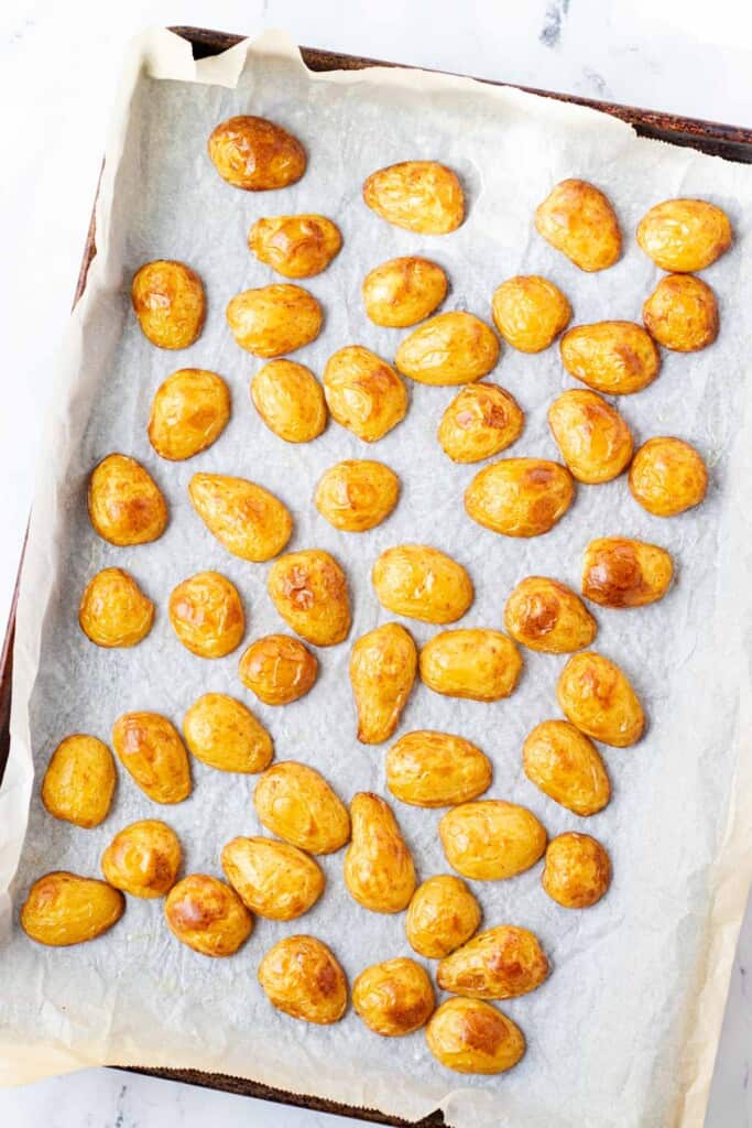 Roasted potatoes on a baking sheet lined with parchment paper.